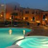 Piscina illuminata di notte con edifici colorati sullo sfondo.