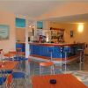 Un bar con tavoli e sedie colorati, un bancone blu e pareti arancioni.