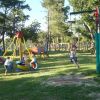 Parco giochi con bambini su una giostra e uno zip-line tra gli alberi.