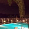 Piscina illuminata di notte con ombrelloni e palme.