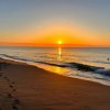 Una spiaggia al tramonto con un cielo arancione e mare calmo.