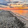 Una spiaggia con lettini vuoti al tramonto e cielo variopinto.