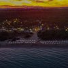 Spiaggia al tramonto con ombrelloni visti dall'alto.