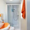 Bagno con doccia e asciugamani arancioni.