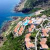 Vista aerea di un resort con tetti rossi vicino alla costa rocciosa e mare blu.