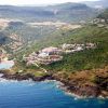 Paesaggio costiero collinare con edifici colorati vicino al mare.