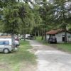 Un campeggio con auto e camper tra gli alberi vicino a un edificio con tetto rosso.