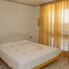 Camera da letto con letto matrimoniale, tende arancioni e sedia di legno.