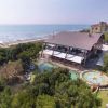 Vista aerea di un edificio con piscina vicino al mare e circondato da vegetazione.