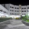 Cortile notturno di un edificio moderno con pavimento a zig-zag e piante verdi.