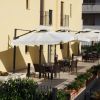 Terrazza con tavoli e sedie ombreggiati da grandi ombrelloni bianchi.