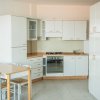 Cucina moderna bianca con forno e tavolo.