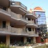 Edificio moderno con balconi in cemento e vetri riflettenti, circondato da piante.