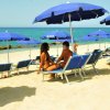 Due persone sotto ombrelloni blu in spiaggia.