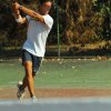 Uomo gioca a tennis su un campo all'aperto.