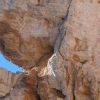 Uomo arrampica su una grande roccia.
