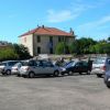Parcheggio pieno di auto vicino a una casa con tetto rosso.