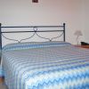 Un letto matrimoniale con copriletto a zigzag blu e verde, tra due comodini con lampade.