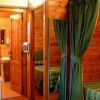 Interno di una stanza in legno con lavandino e letto, separati da una tenda verde.