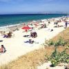 Una spiaggia affollata con ombrelloni colorati e persone che prendono il sole vicino all'acqua.