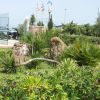 Giardino con piante e cespugli vicino a un cancello verde e bandiere.