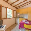 Cucina piccola con mobili gialli, finestra aperta, tavolo apparecchiato e TV.