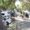 Un campeggio con camper, tende e due persone che camminano tra gli alberi.