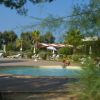 Piscina rotonda tra alberi con un bambino che gioca in acqua e lettini in lontananza.