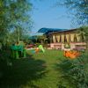 Spazio verde con giochi per bambini e una struttura con tende gialle.