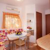 Cucina e salotto colorati con divano floreale e tavolo, ben illuminata.