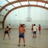 Persone giocano a pallavolo in una struttura coperta con tetto ad arco.