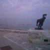 Statua su pietra vicino al mare, oceano calmo al tramonto.