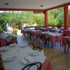 Una terrazza con tavoli apparecchiati, tovaglie a quadri rossi e bianchi, circondata dalla natura.