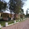 Bungalow gialli allineati lungo una strada sterrata in un'area verde.