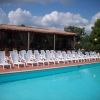 Piscina con sedie a sdraio bianche allineate e un edificio con tetto in tegole.