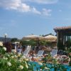 Piscina con sedie a sdraio, persone che si rilassano e ombrelloni beige.