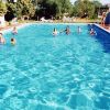 Piscina all'aperto con persone che nuotano e si rilassano intorno.