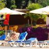 Lettini e ombrelloni bianchi vicino a una piscina, circondati da piante e fiori.