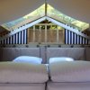 Interno di una tenda con letto matrimoniale sotto soffitto spiovente.