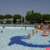Piscina con bambini e ombrelloni arancioni.