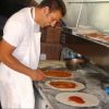 Uomo prepara delle pizze in una cucina.