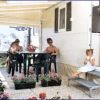 Persone sedute a un tavolo all'aperto vicino a un camper, con fiori intorno.